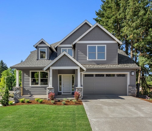 Suburban home exterior on bright sunny day, with large yard and covered porch