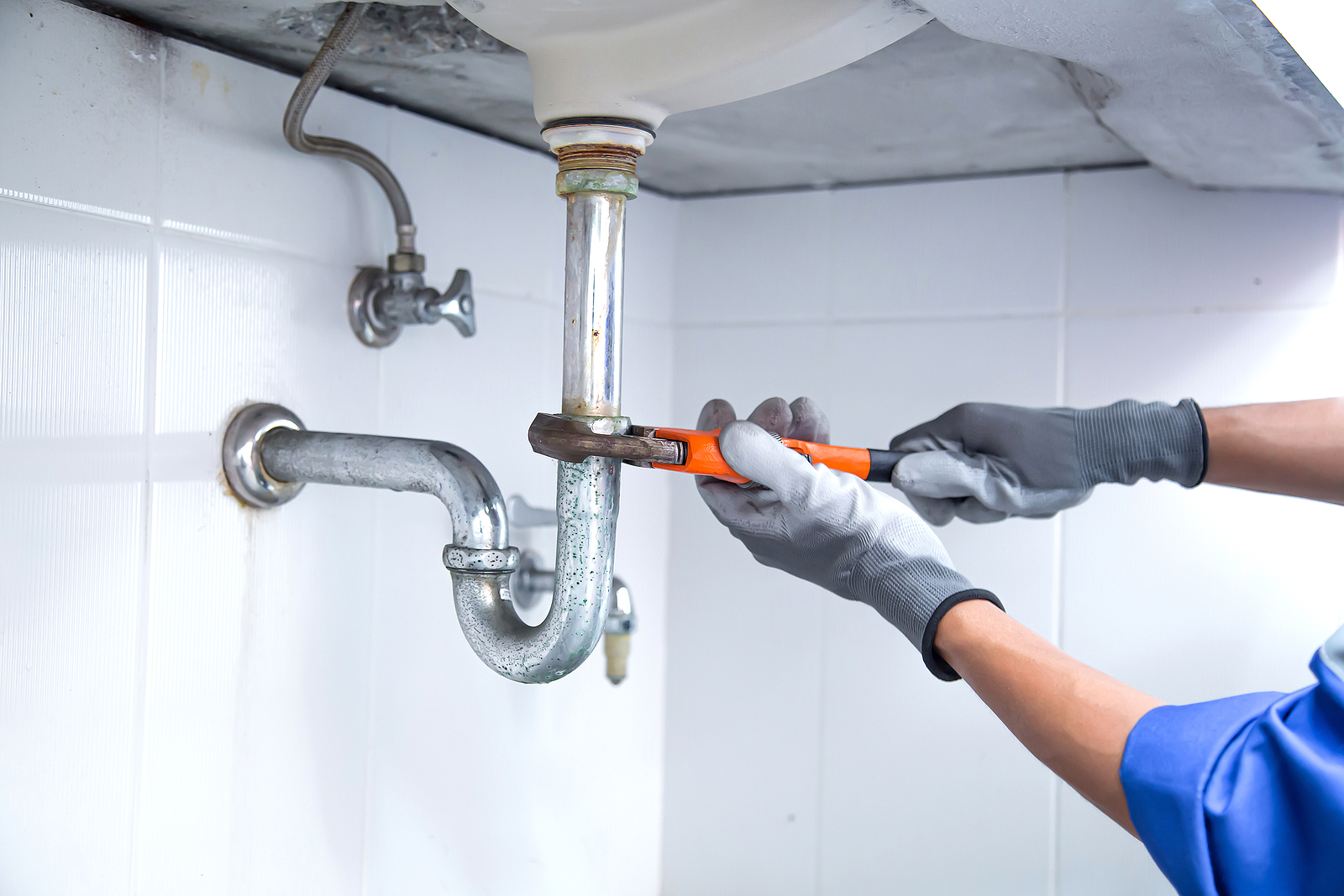 Technician Plumber Using A Wrench To Repair A Water Pipe Under T